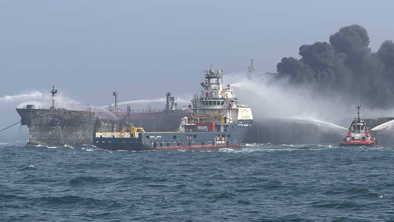 Ships at sea being sprayed with water, billowing smoke.