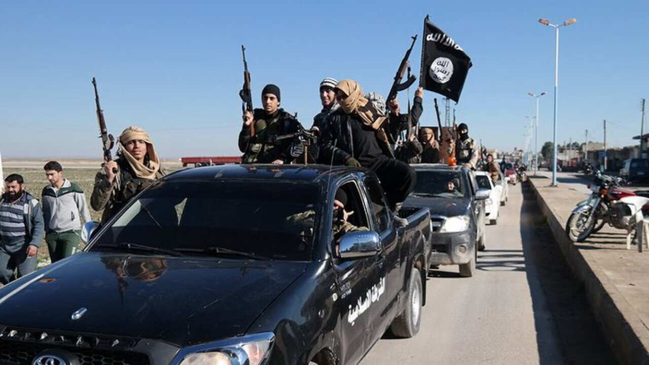 Islamic State militants pass by a convoy in Tel Abyad, northeast Syria.