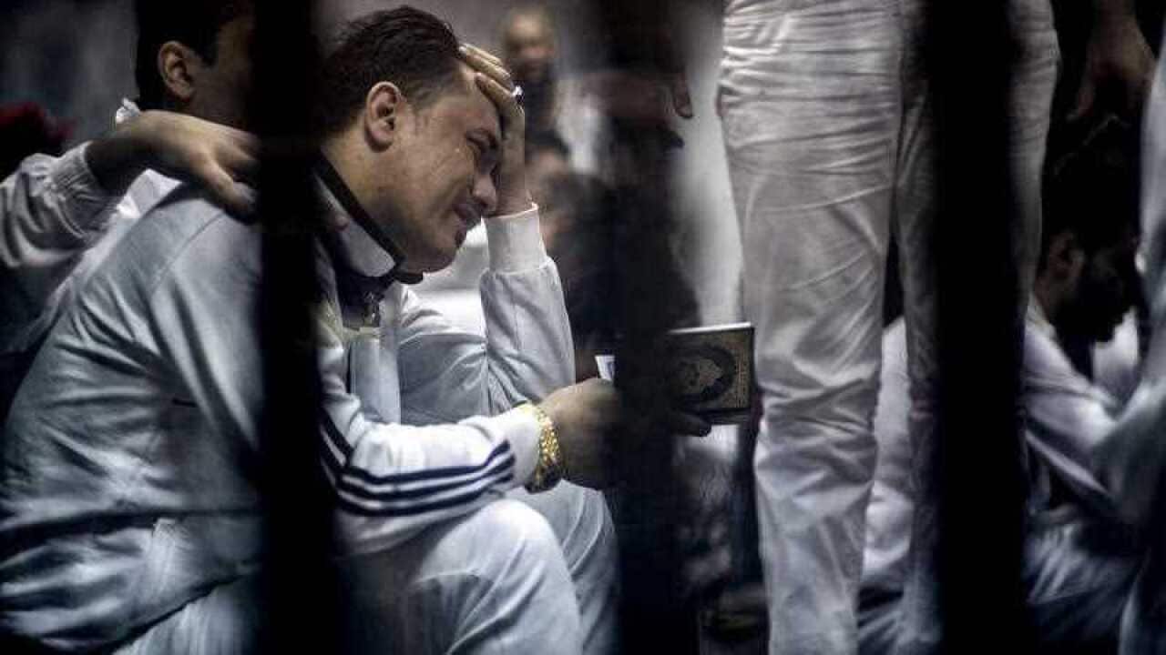 A defendant holds a Quran in a courtroom cage