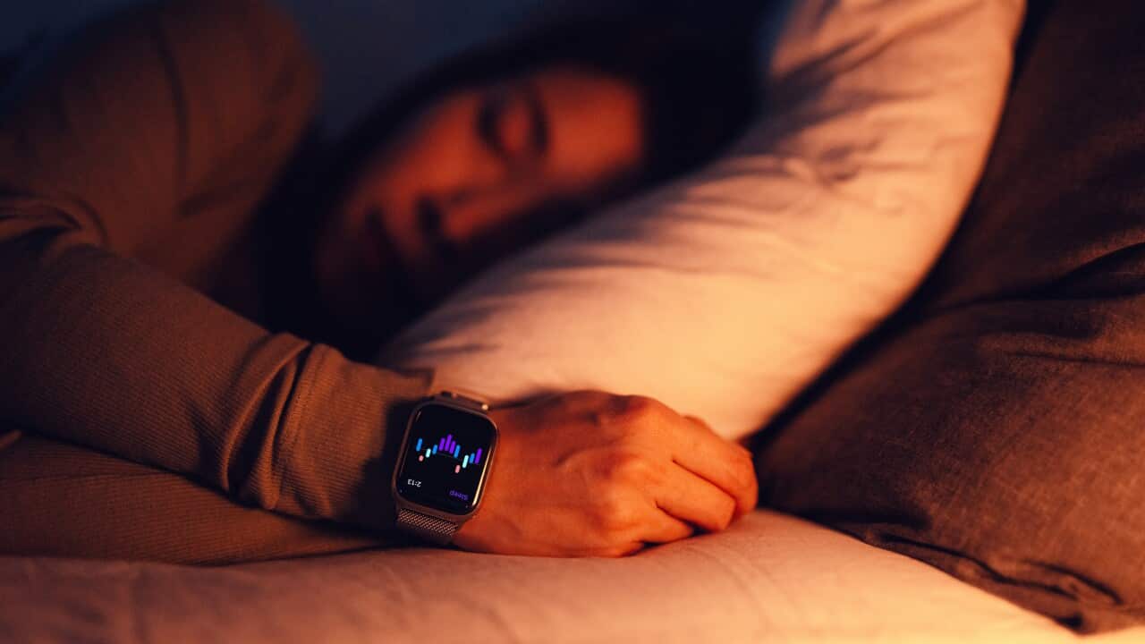 Young Asian woman using sleep tracker app on smartwatch to monitor her sleep cycle