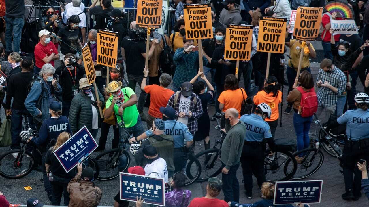 Police officers stand between protesters supporting President Trump (bottom) and people participating in a protest in support of counting all votes.
