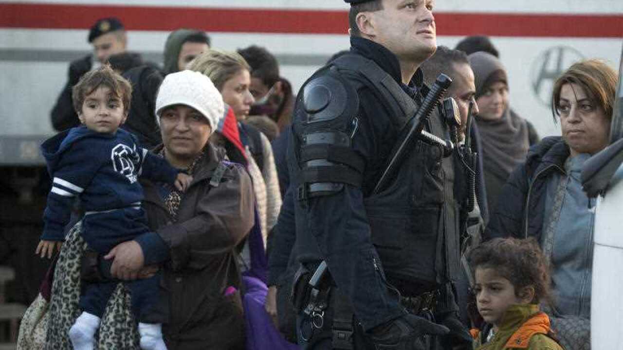 A Croatian police officer assists migrants to board a bus in Cakovec, near the Croatian-Slovenian border