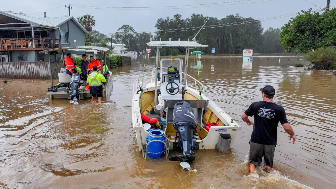 People in white rescue boats are passing through muddy floodwater.