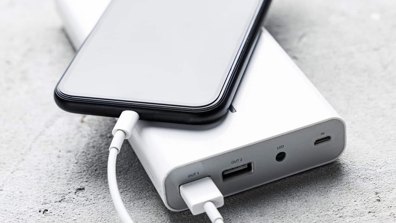 A mobile phone plugged into a portable power bank.