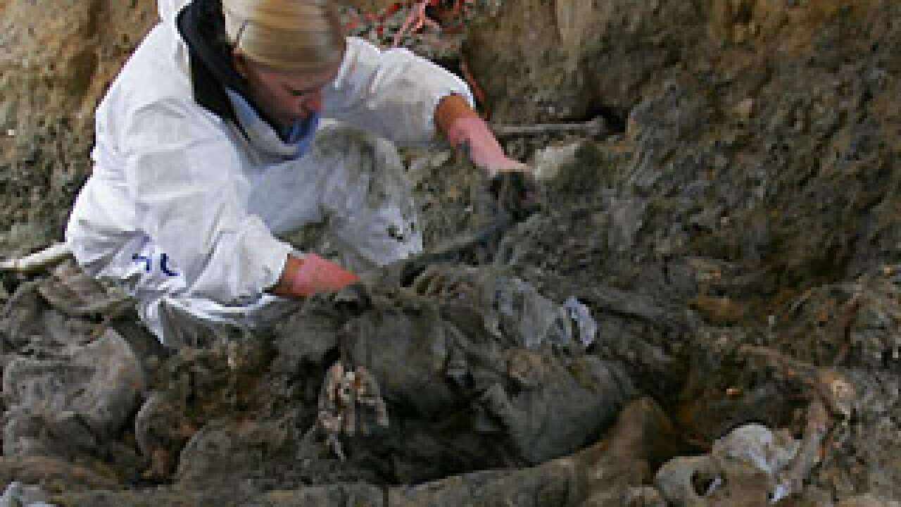 A forensic expert examines a mass grave near Srebrenica