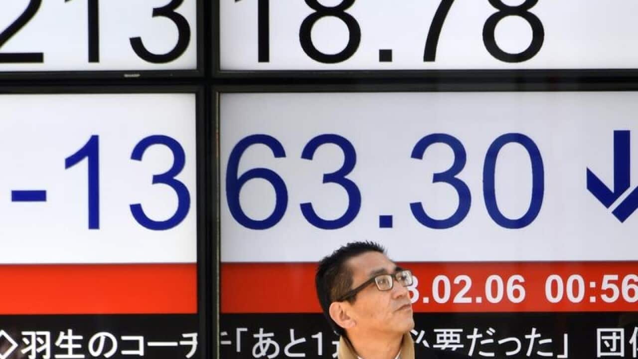 A man stands in front a stock market board in Tokyo