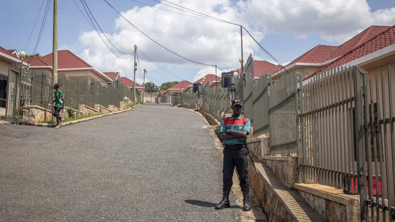 A security guard stands next to a fence