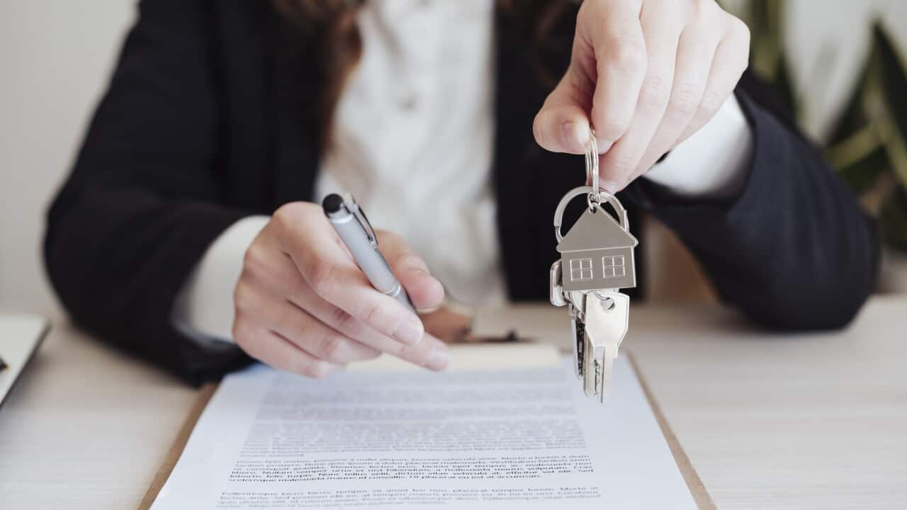 Saleswoman holding house keys and pen at office