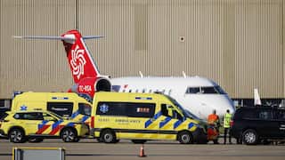 Three ambulances parked around a plane on airport tarmac.