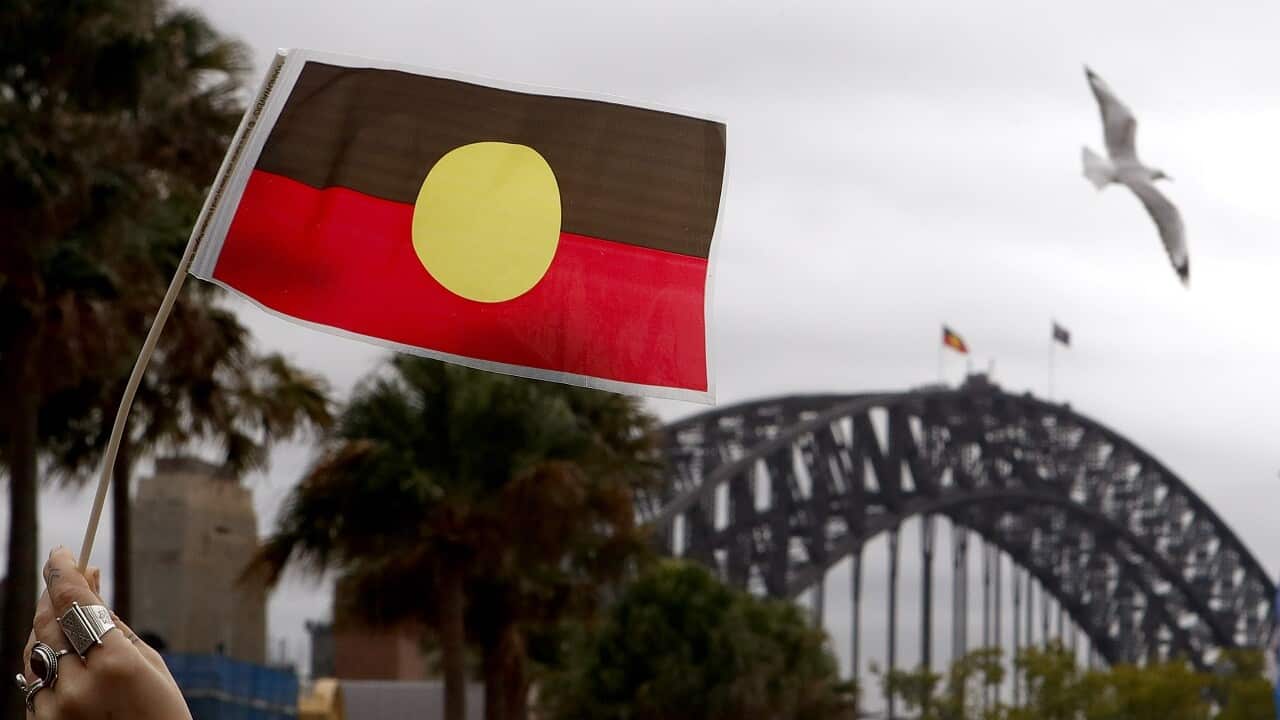 A woman holds an Australian Aboriginal Flag