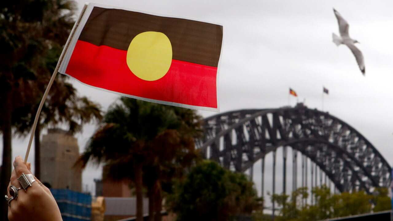 A woman holds an Australian Aboriginal Flag (AAP).