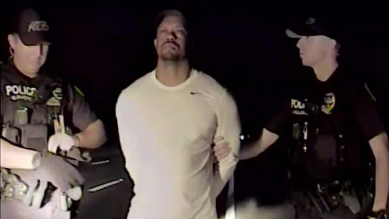 Golfer Tiger Woods stands between two police officers