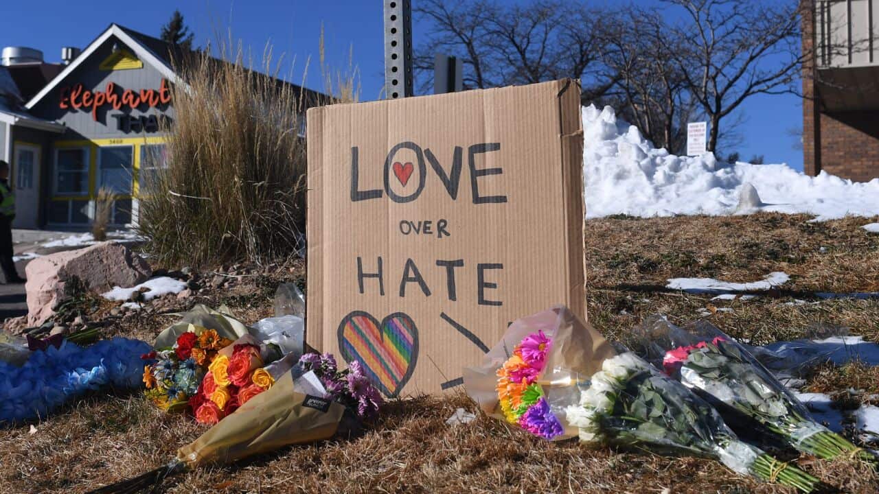 Bouquets of flowers and a sign reading "Love Over Hate" on some grass