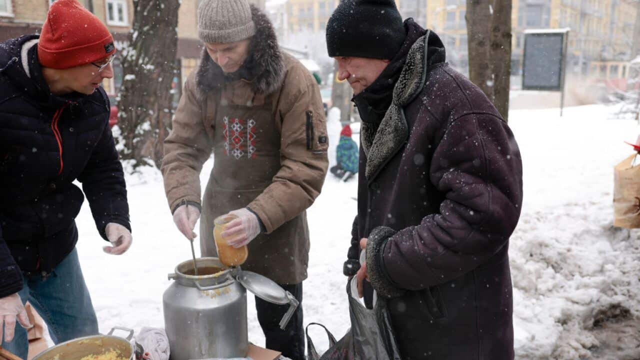 Elderly people receive food and gloves from a charity organisation in a snow covered street in Kyiv, Ukraine.