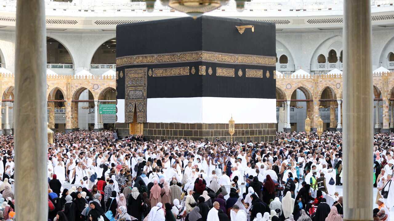 A large group of people circling a large cubic shrine.