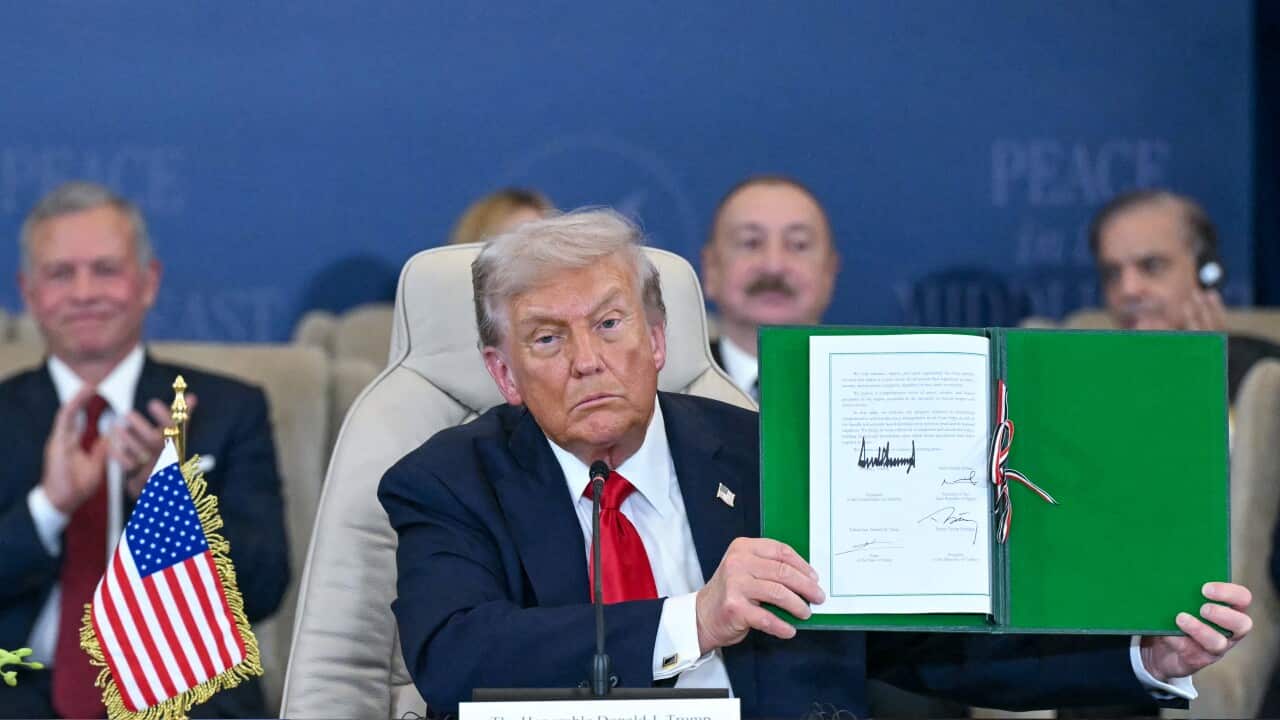 A man in a suit holds up and shows a signed document.