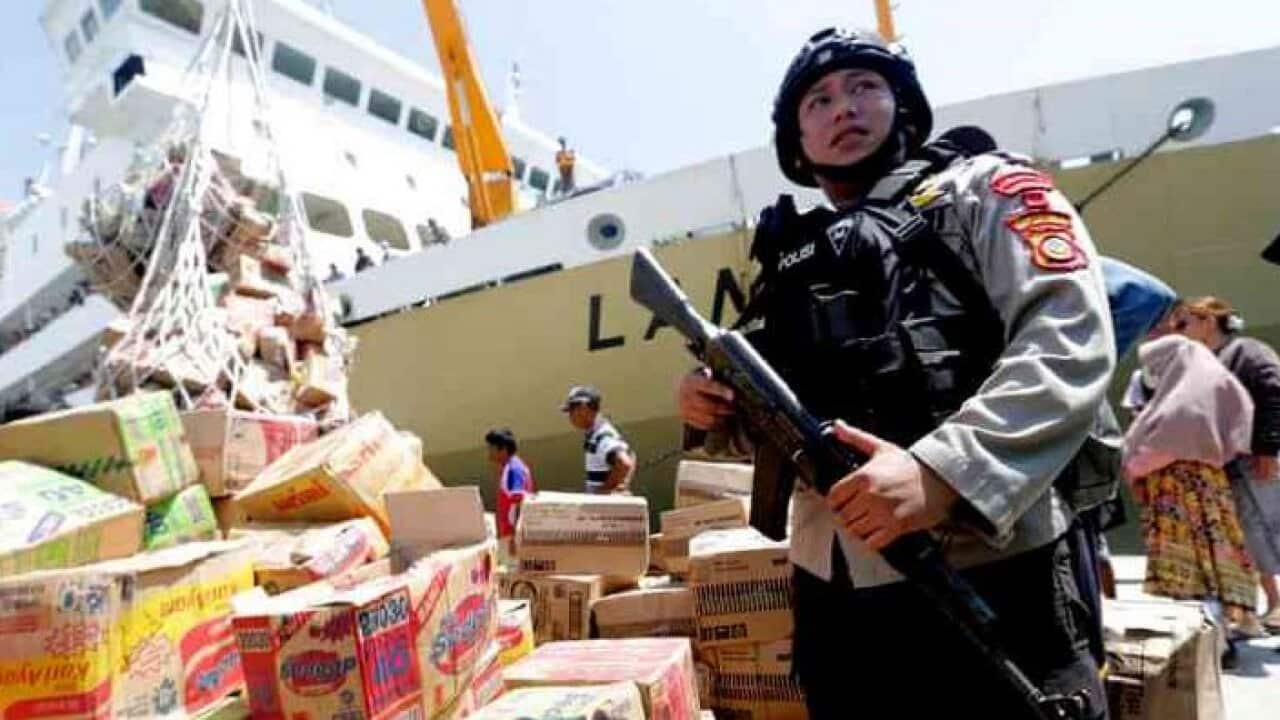 A policeman guards a delivery of food and aid at Palu port on Tuesday , 02 Oct 2018.