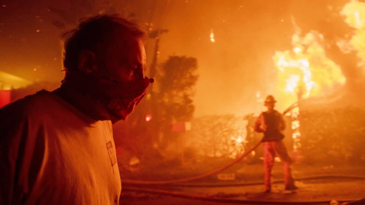 A man walks past a burning home during the Getty Fire, Monday, Oct. 28, 2019, in Los Angeles, California.