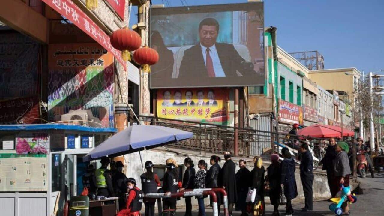 A screen shows Chinese President Xi Jinping in Hotan in western China's Xinjiang region.