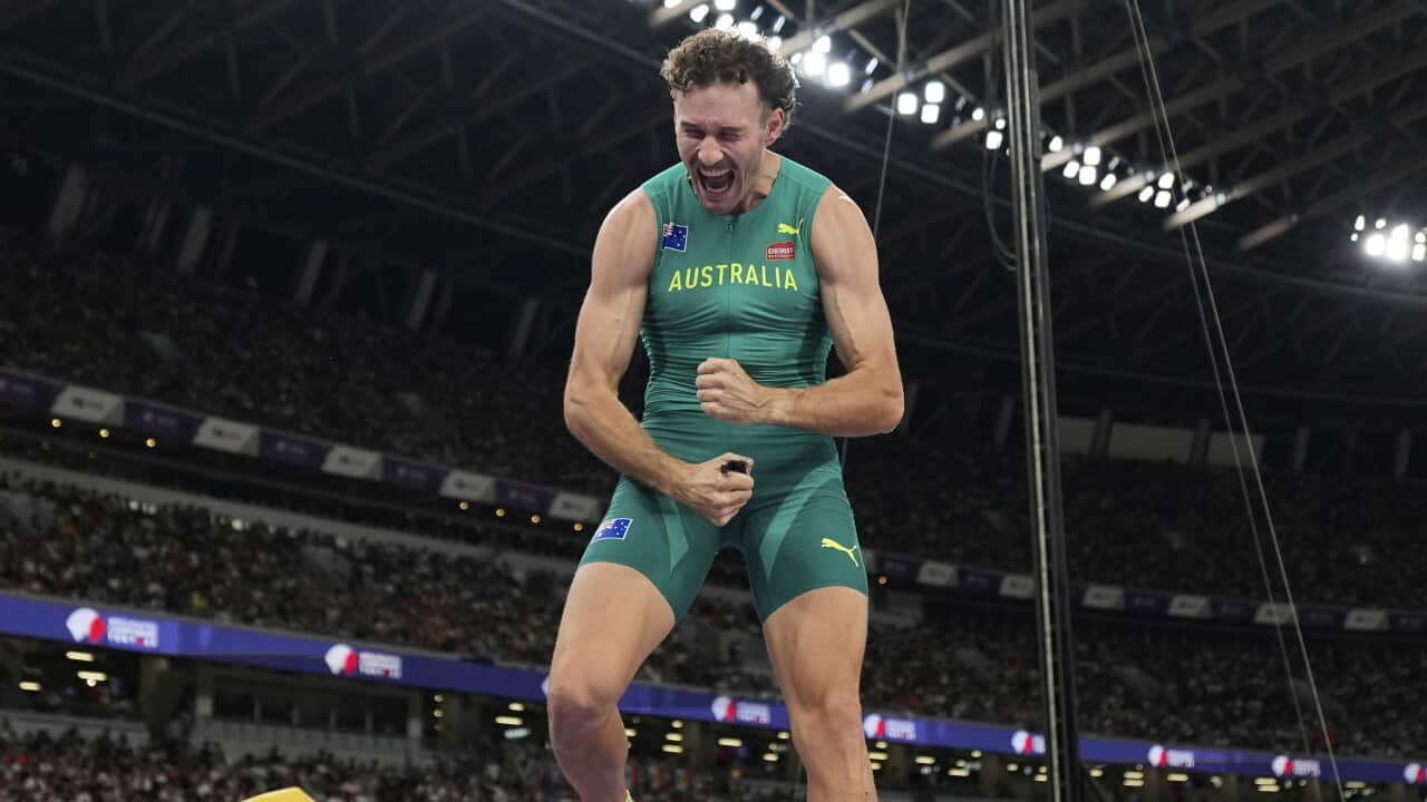 A man in a green athletics one-piece outfit with Australia written in gold lettering on the front celebrates