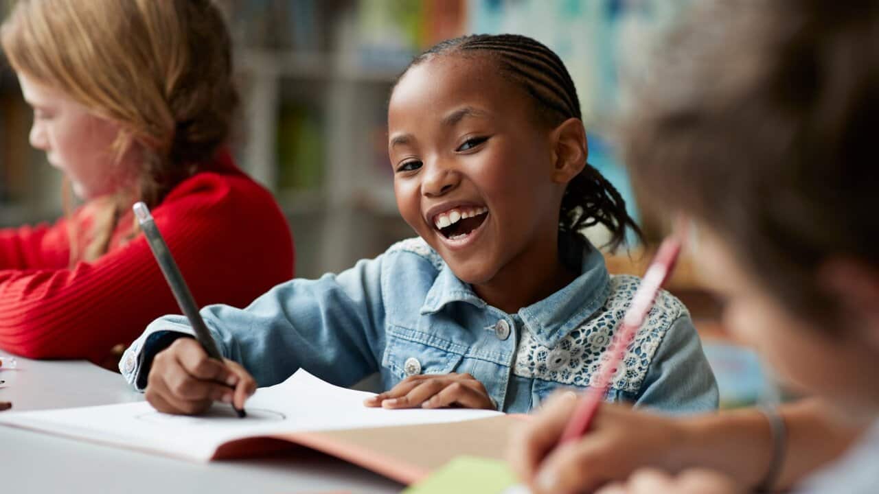 Portrait of schoolgirl drawing at the school library and laughing