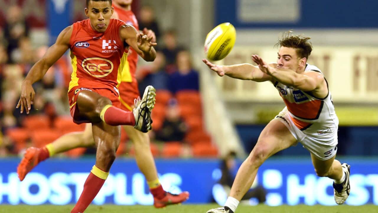 Touk Miller of the Gold Coast Suns (left) kicks