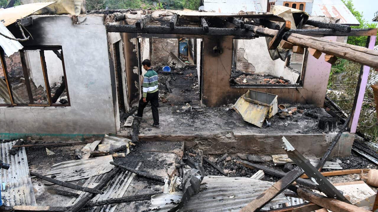 A boy walks through a damaged and burned-out home.
