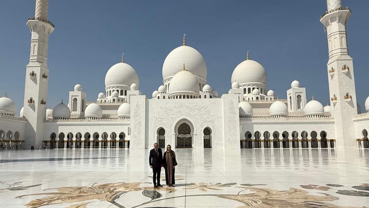 A couple standing in front of a mosque.