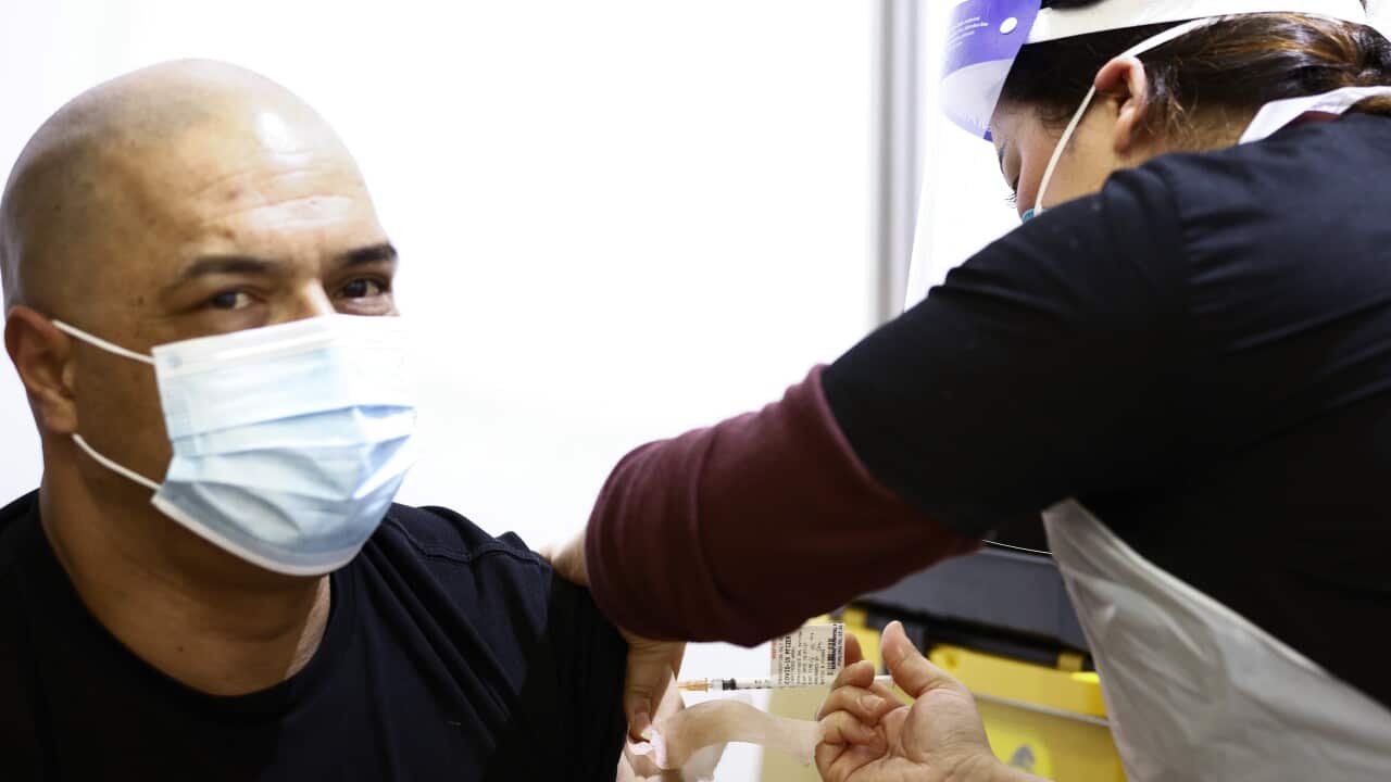 A health worker (right) administers a Pfizer vaccination to a person at a mass coronavirus vaccination hub at the Showgrounds in Melbourne, Monday, July 19, 2021. (AAP Image/Daniel Pockett) NO ARCHIVING