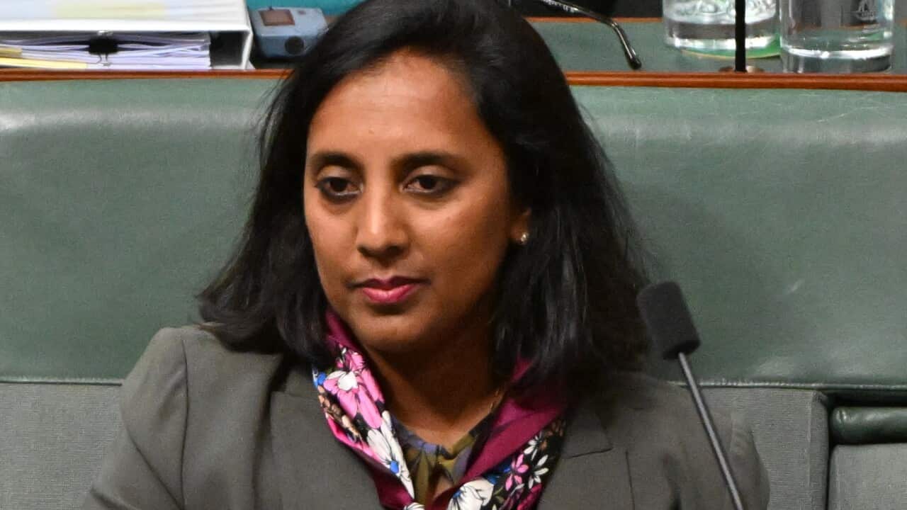 A woman wearing formal attire seated in the House of Representatives.