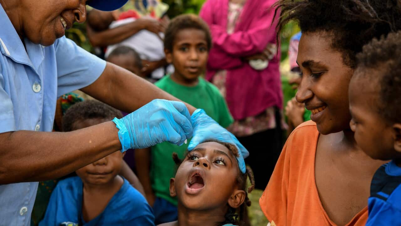 A nurse administers an oral vaccination to a child with their mouth open