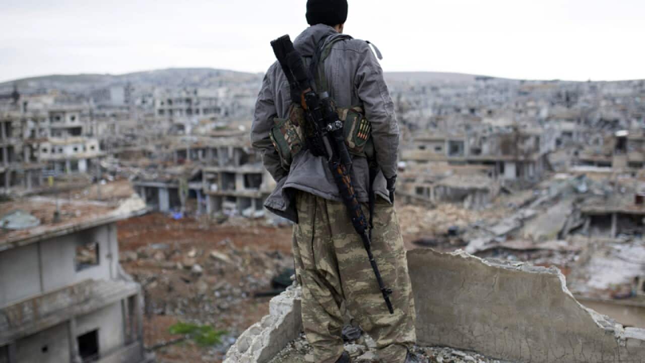 A Syrian Kurdish sniper looks out to Kobani