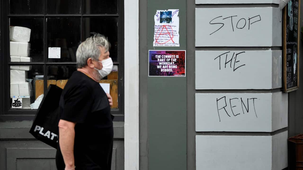 Man walks past a shop with 'Stop the Rent' sign.