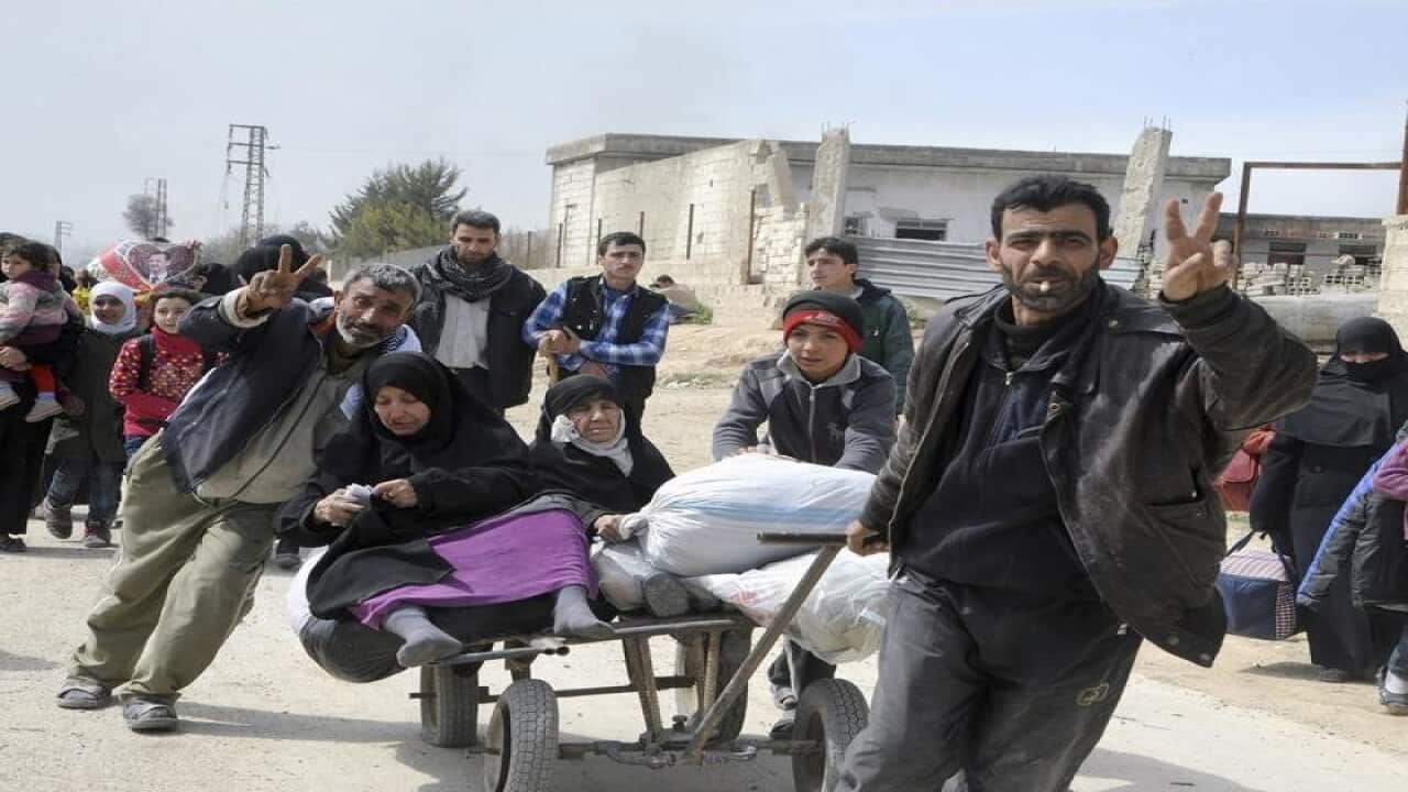 Syrian civilians with their belongings flashing the victory sign.