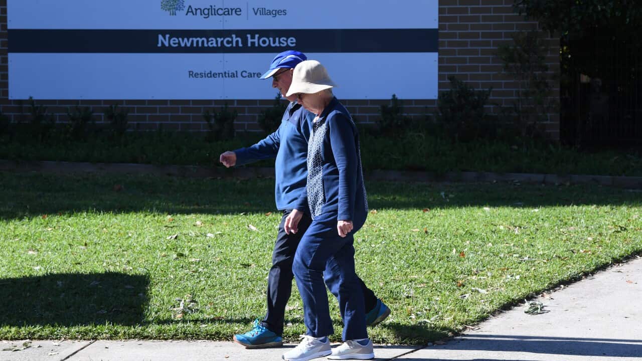 A couple are seen walking out of Anglicare's Newmarch House in Sydney, the location of a major COVID-19 outbreak.