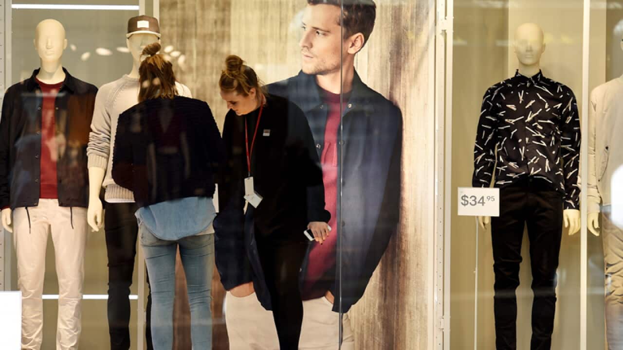 Window dressers fix mannequins in a store in Sydney