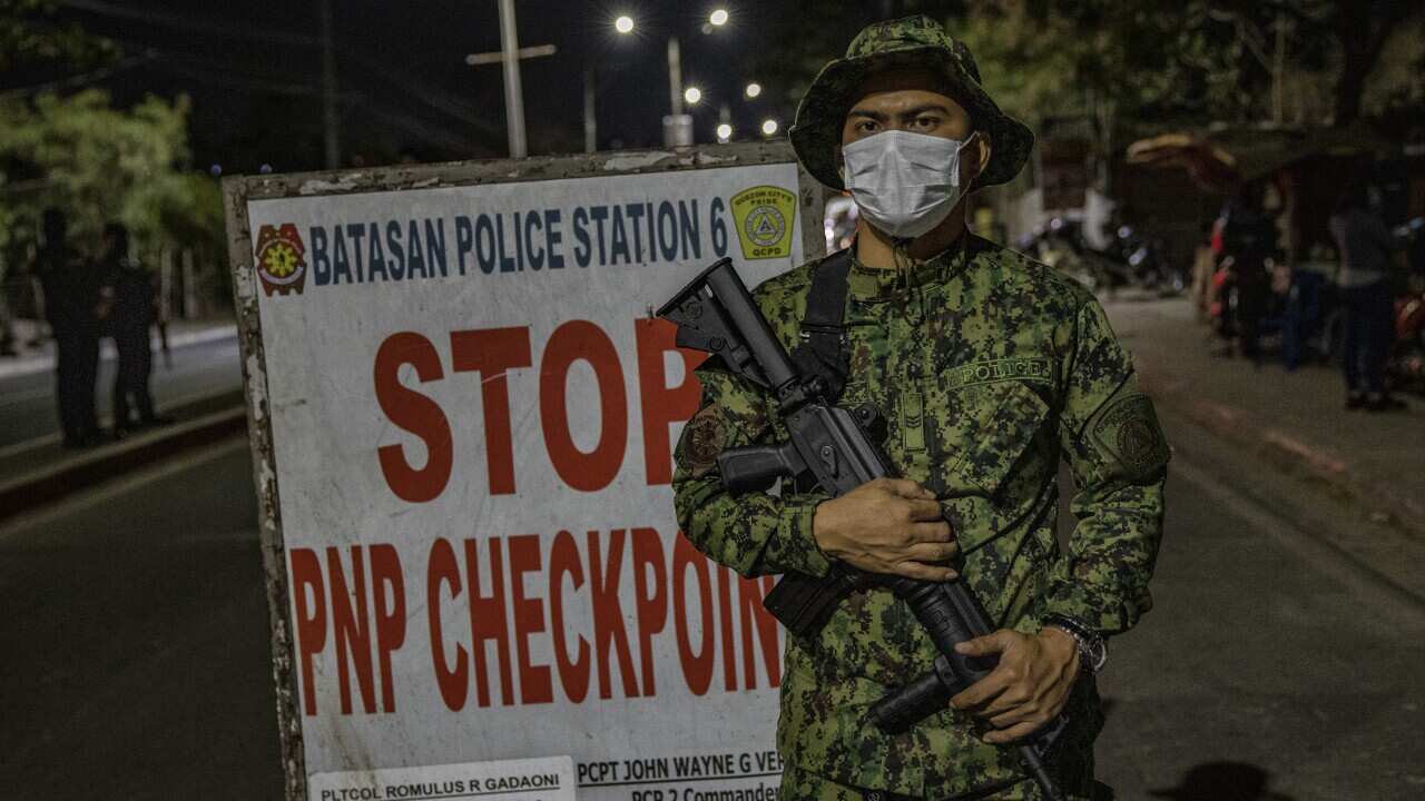 A police officer is seen wearing a face mask as he stands guard at a checkpoint in Manila.
