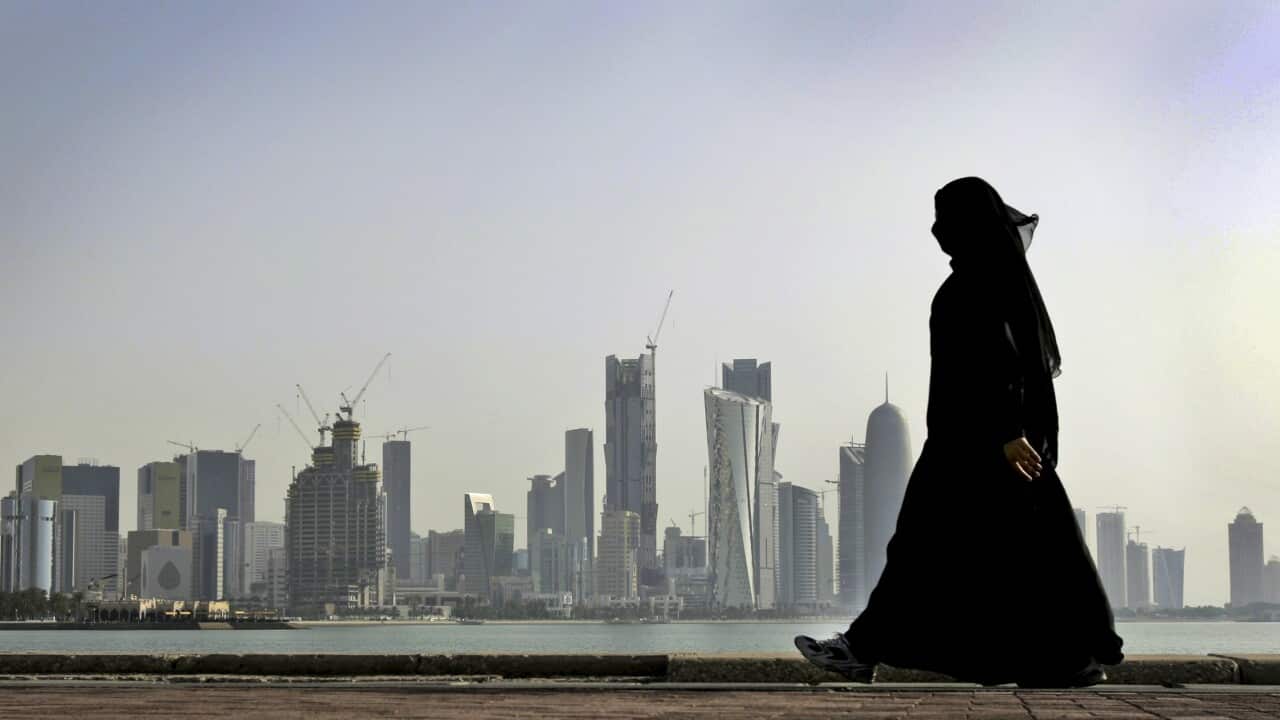 FILE- In this May 14, 2010 file photo, a Qatari woman walks in front of the city skyline in Doha, Qatar.
