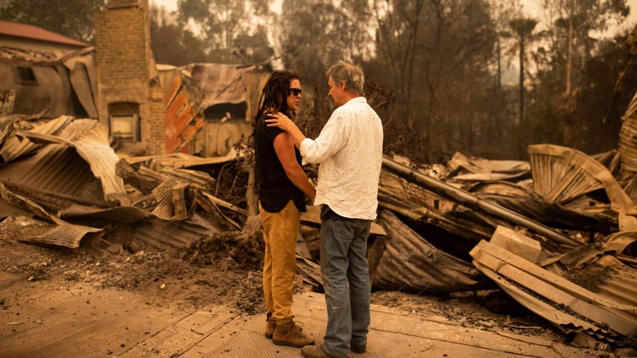 Business owner Sally Anne Wilson (left) stands in front of her destroyed shop with her partner Christopher Lee in Cobargo