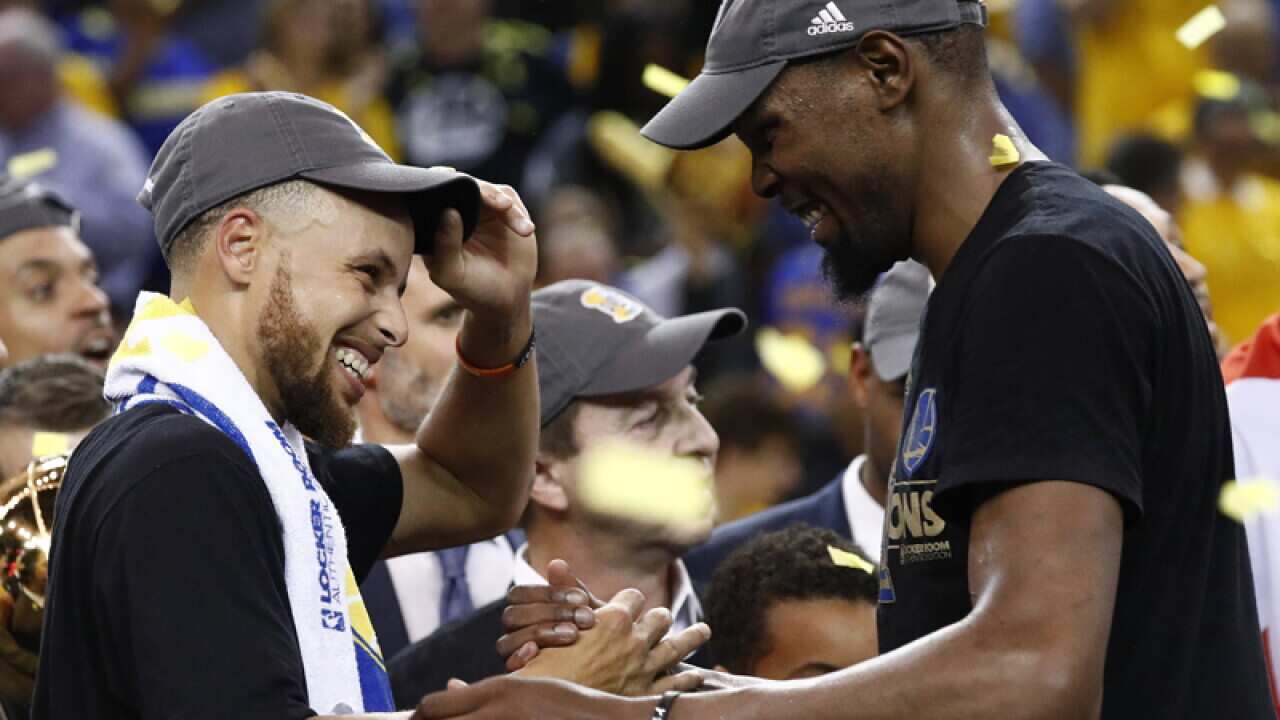 Warriors player Kevin Durant (R) laughs with teammate Stephen Curry