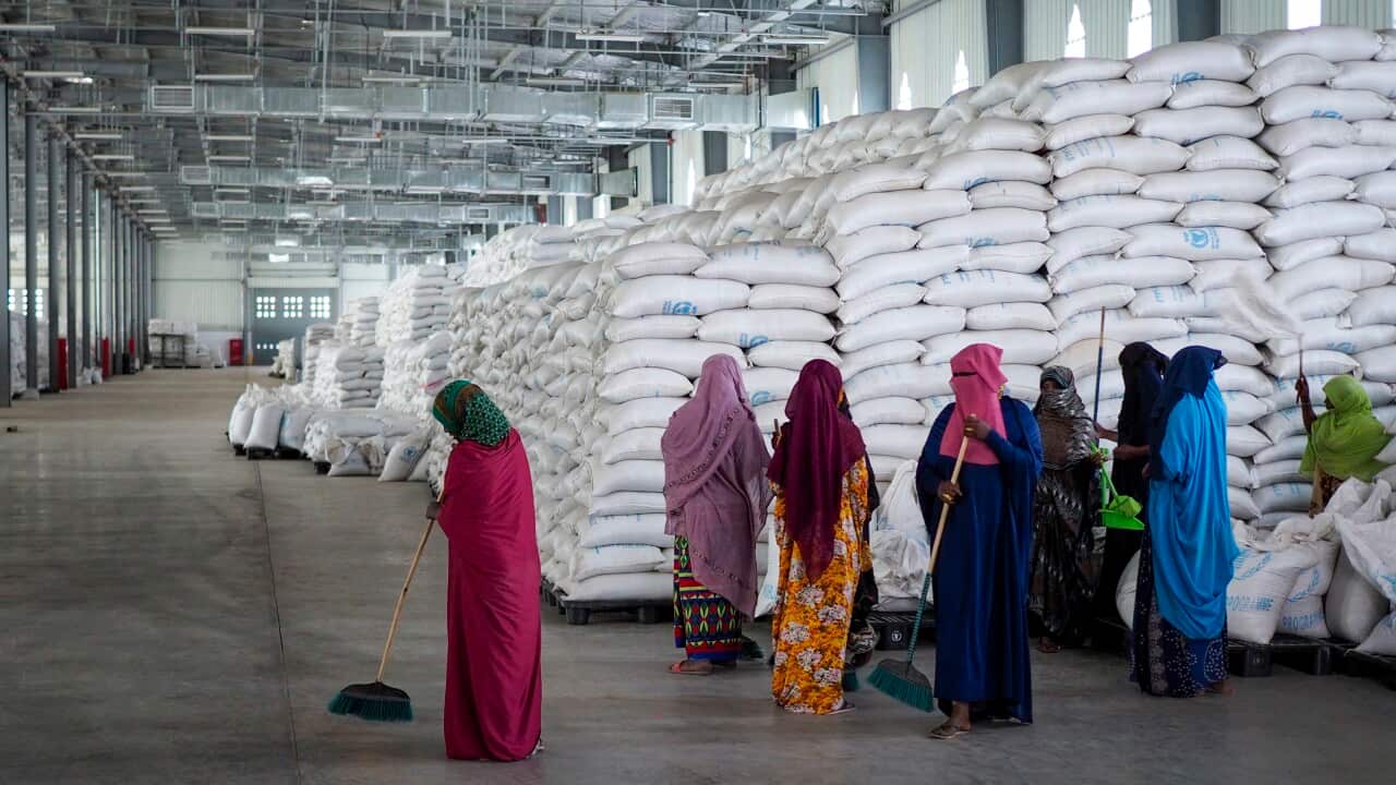Workers clean the floor as sacks of food earmarked for the Tigray and Afar regions sits in piles in a warehouse of the World Food Programme (WFP) in Semera, the regional capital for the Afar region, in Ethiopia.