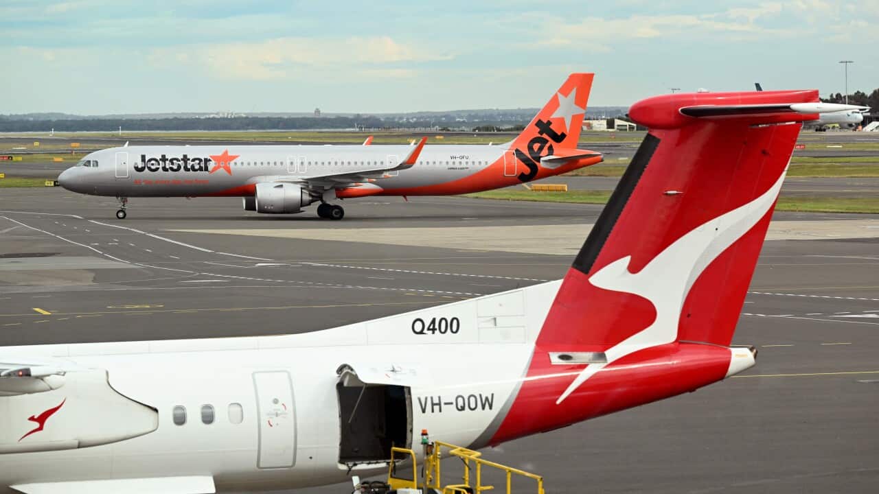 A Qantas plane at an airport with a Jetstar plane in the background.