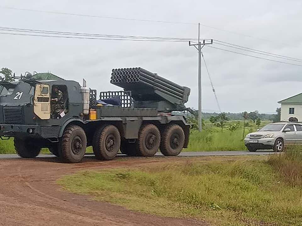 A large vehicle with a rocket launcher driving on a dirt road.