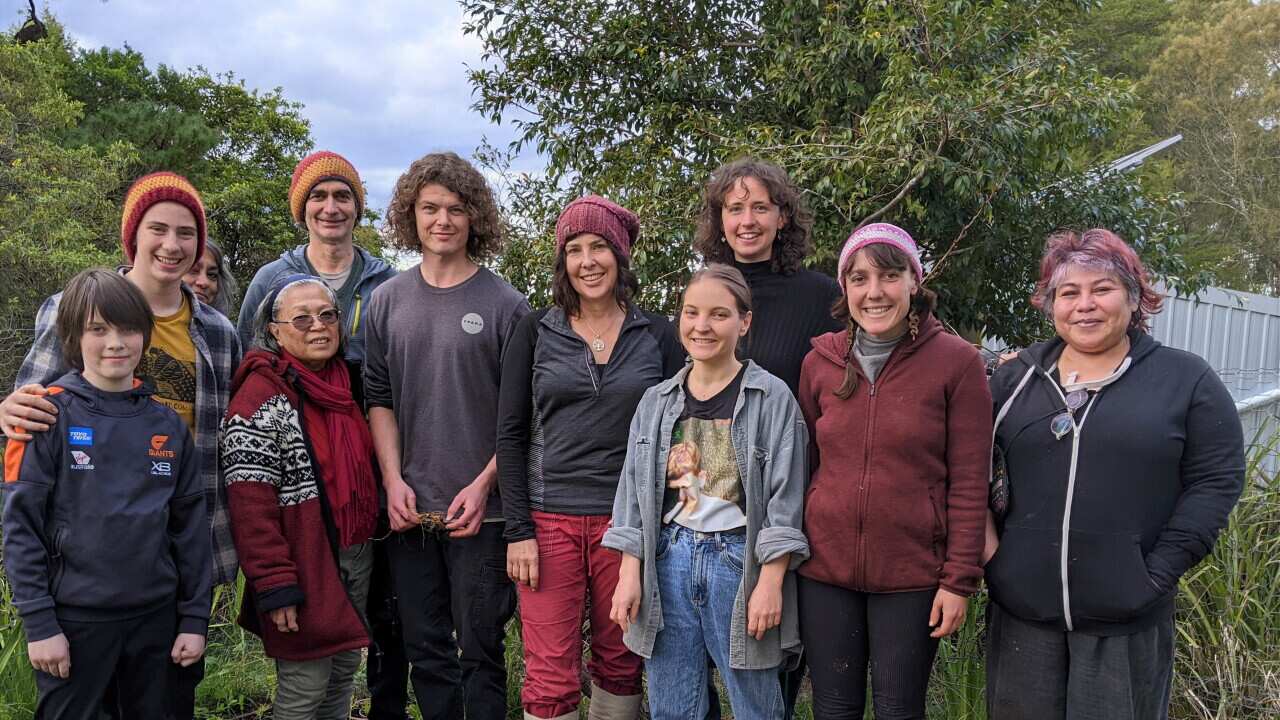 Manu Prigioni (centre) standing with a diverse team of volunteers.