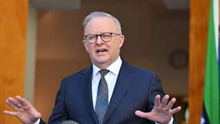 Anthony Albanese speaking at a podium in a navy suit and tie.