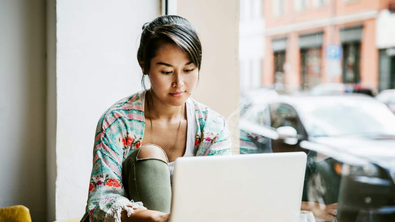 Young Woman Working On Laptop In Cafe Window