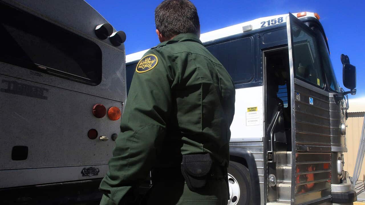 A U.S. border patrol agent walks past buses used to transport detained immigrants in Texas