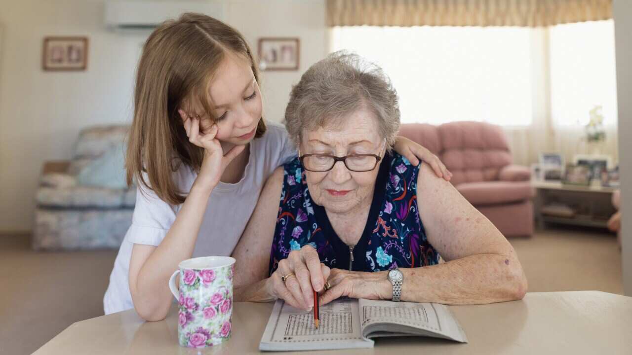 Grandmother and granddaughter doing crossword puzzle together