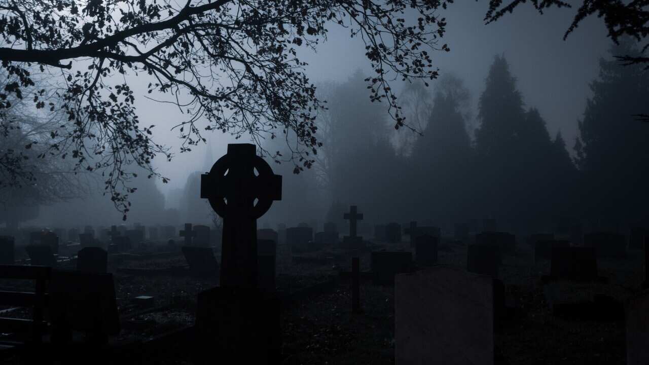 Spooky gravestones in a churchyard on a foggy winters mysterious night.