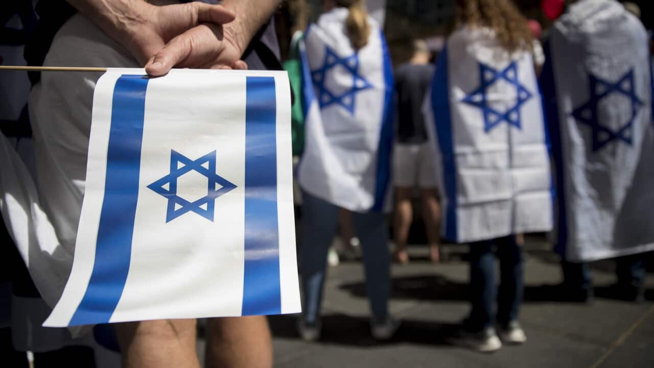 A person holding an Israeli flag behind them and others wearing the flags as capes.